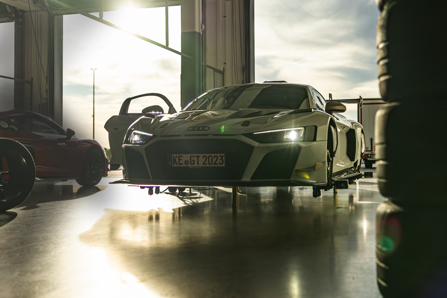 schwarz weißer XGT mit leuchtenden Lichtern auf Hebebühne in Box aus der seitlichen Frontansicht 