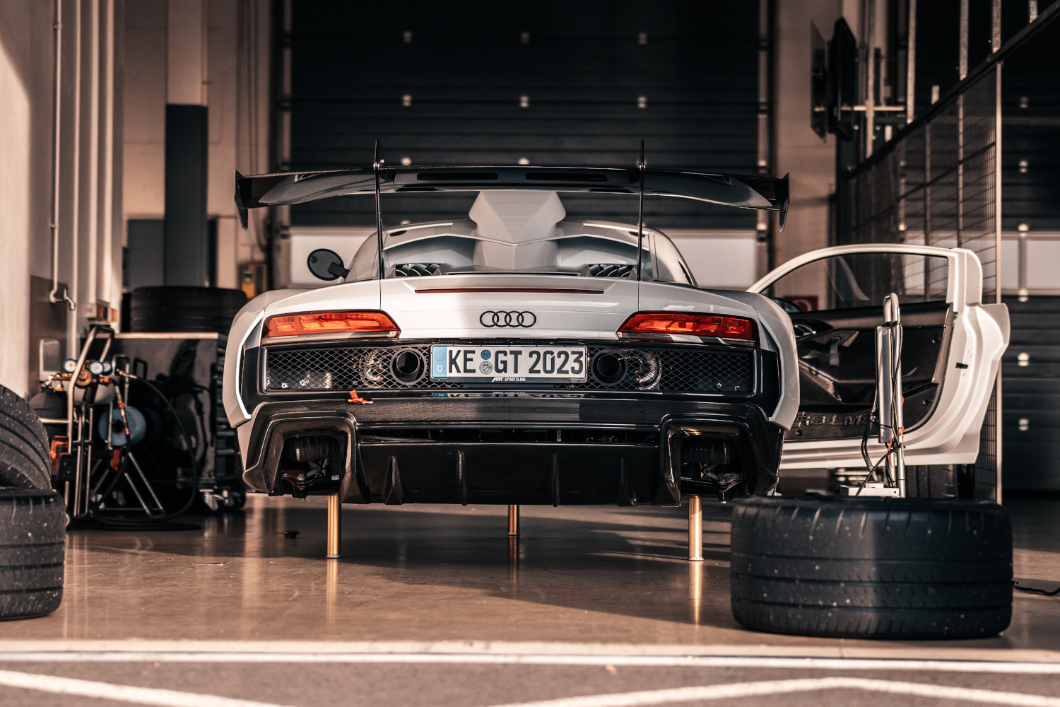 schwarz-weißer XGT aus der Heckansicht beim Reifenwechsel auf Hebebühne in Box