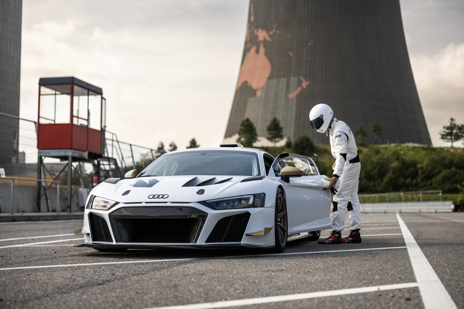 schwarz-weißer XGT azs der seitlichen Frontansicht auf Rennstrecke mit Rennfahrer daneben