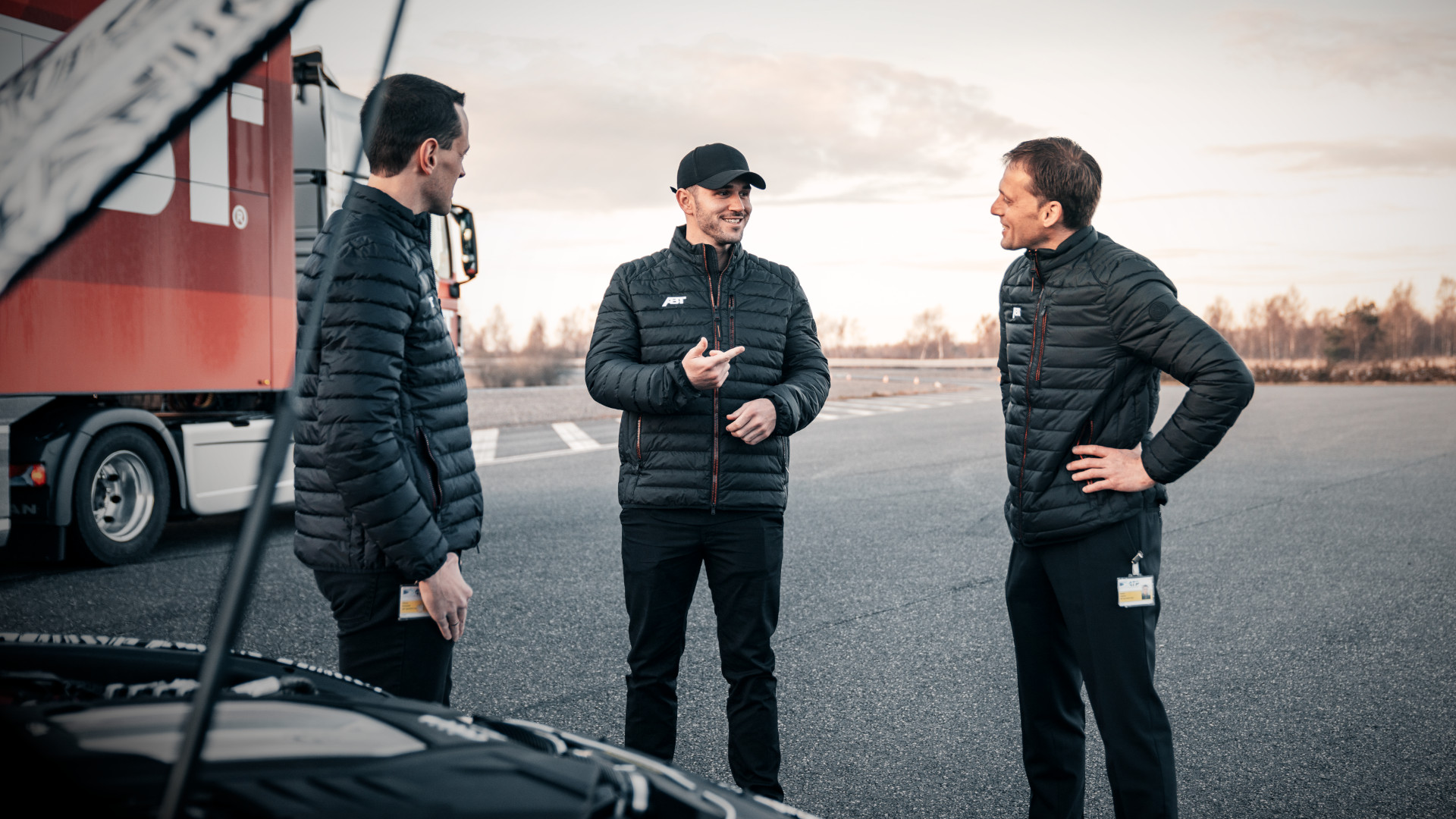 Daniel Abt mit zwei Mitarbeitern vor einer geöffneten Motorhaube
